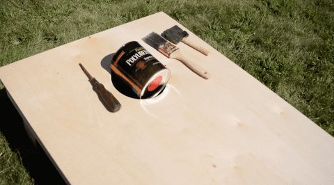 A glossy wooden cornhole board set up on a lawn for outdoor recreation.