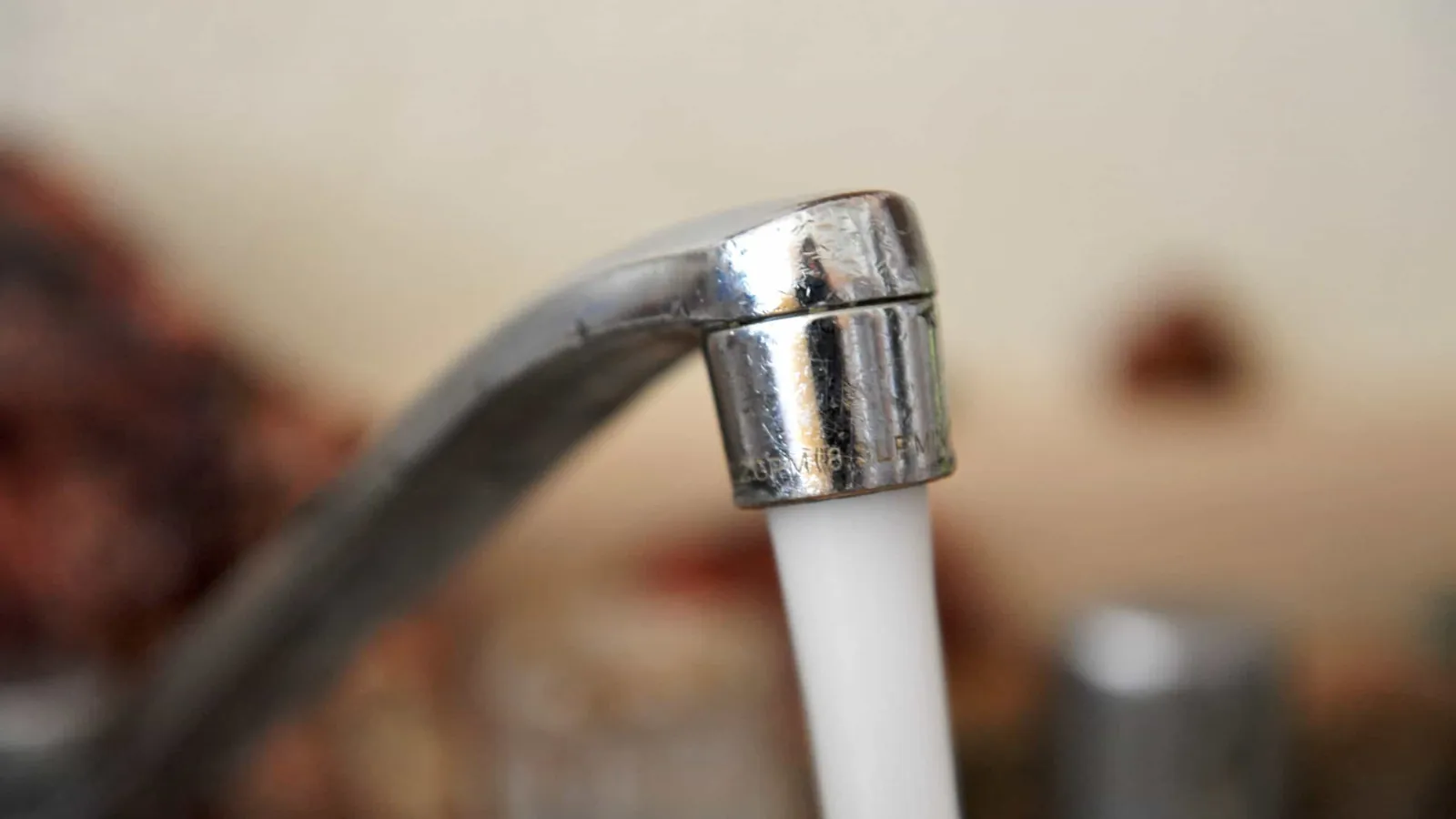 A hand holds two different types of faucet aerators for side-by-side comparison.