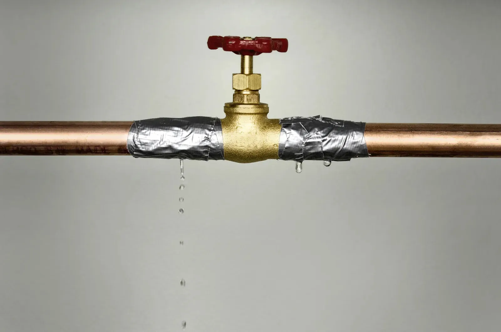 Hands using a wrench to repair a leaking water shut off valve.