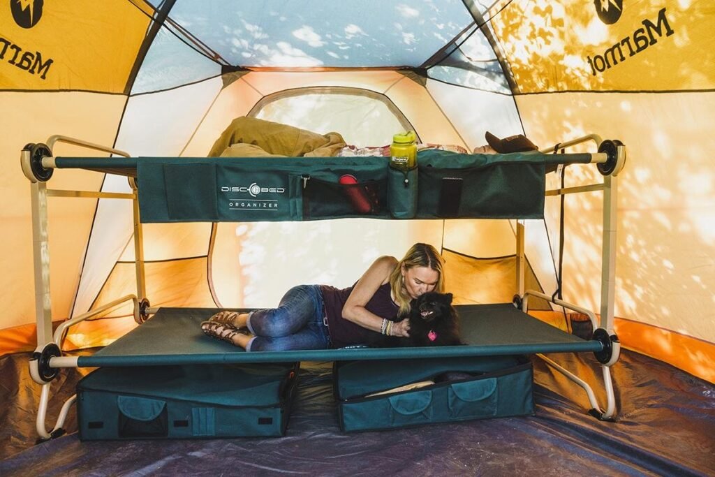 A high-quality camping cot for two on a grassy campsite at dawn