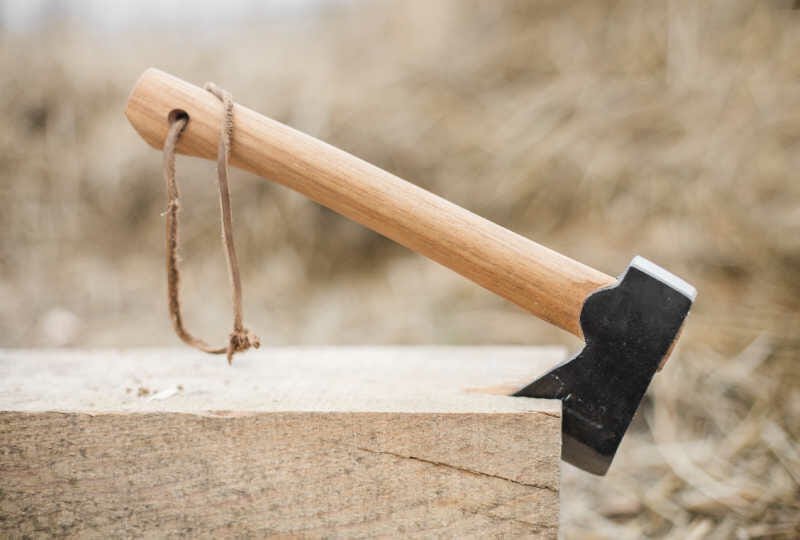 A high-quality hickory axe handle resting on a workbench in a sunlit workshop.