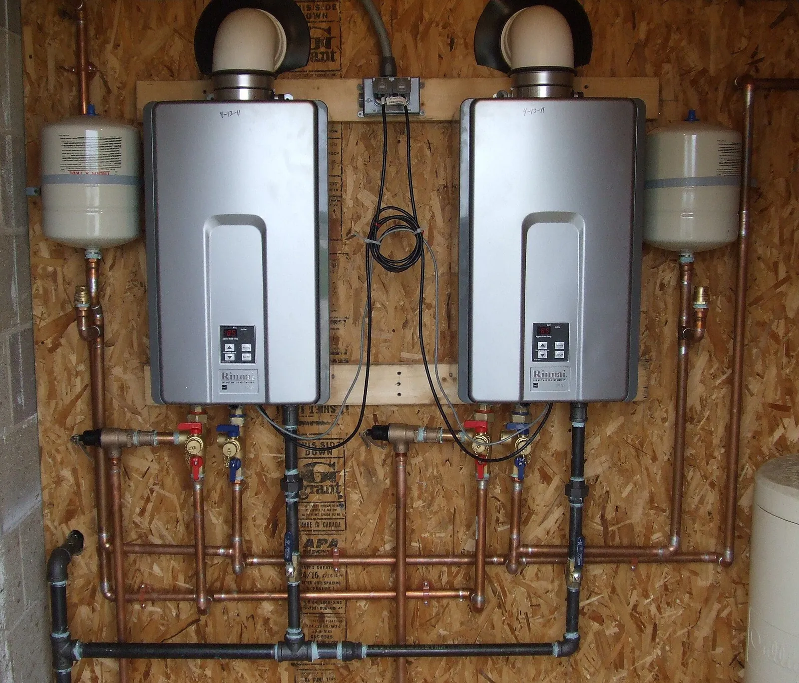 A homeowner inspecting a tankless water heater system and electrical panel.