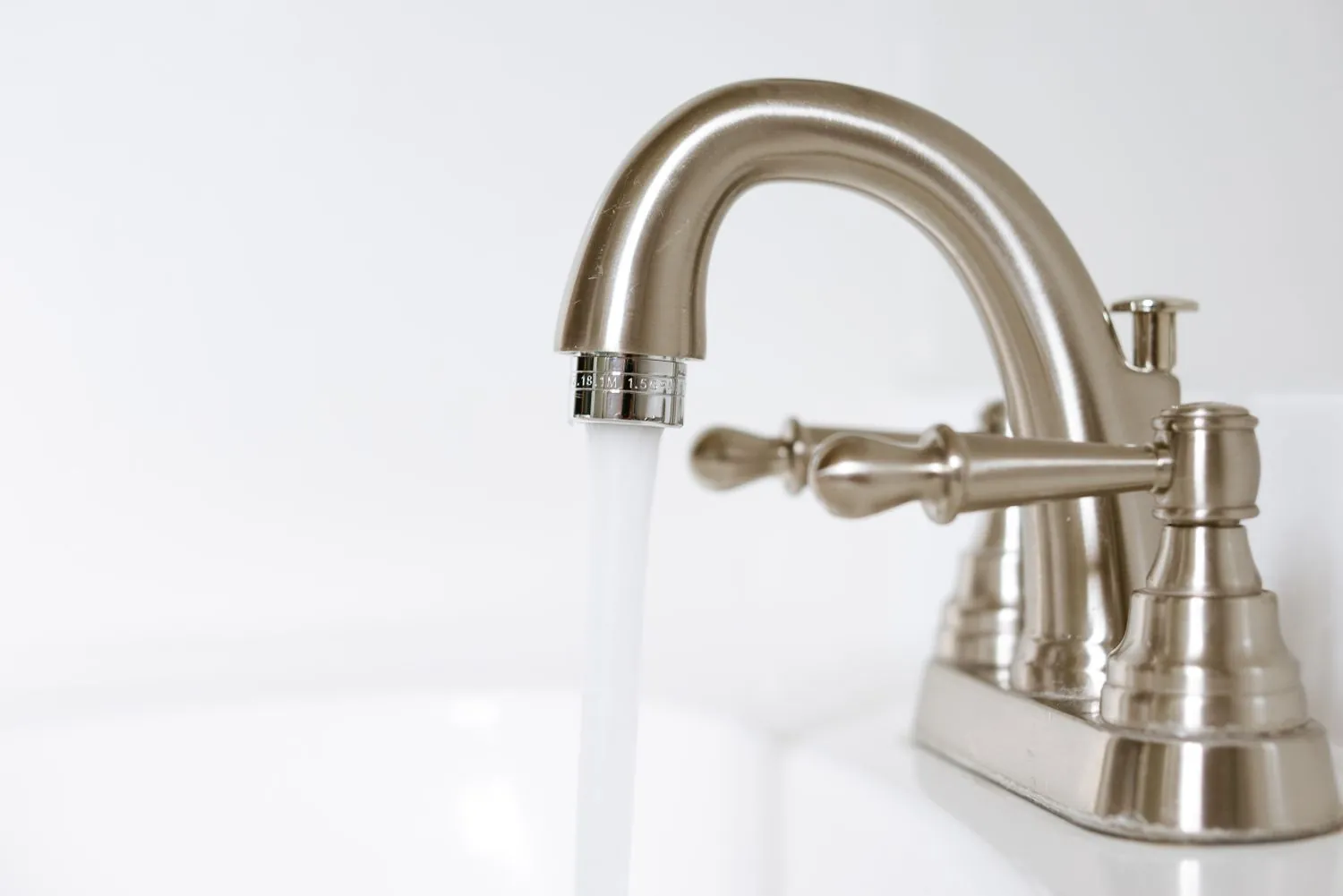 Installing a dual-threaded faucet aerator onto a standard kitchen sink spout.