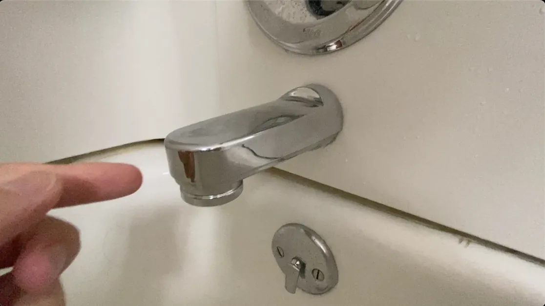 A modern chrome diverter tub spout with a pull-up knob for shower control.