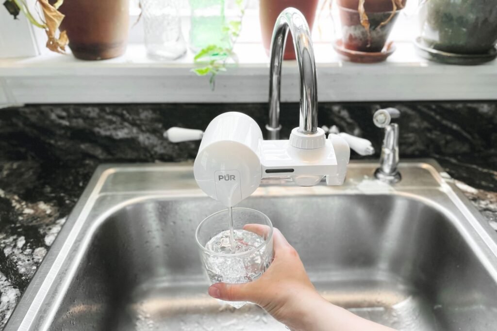 A modern faucet mounted water filter installed on a clean kitchen sink.
