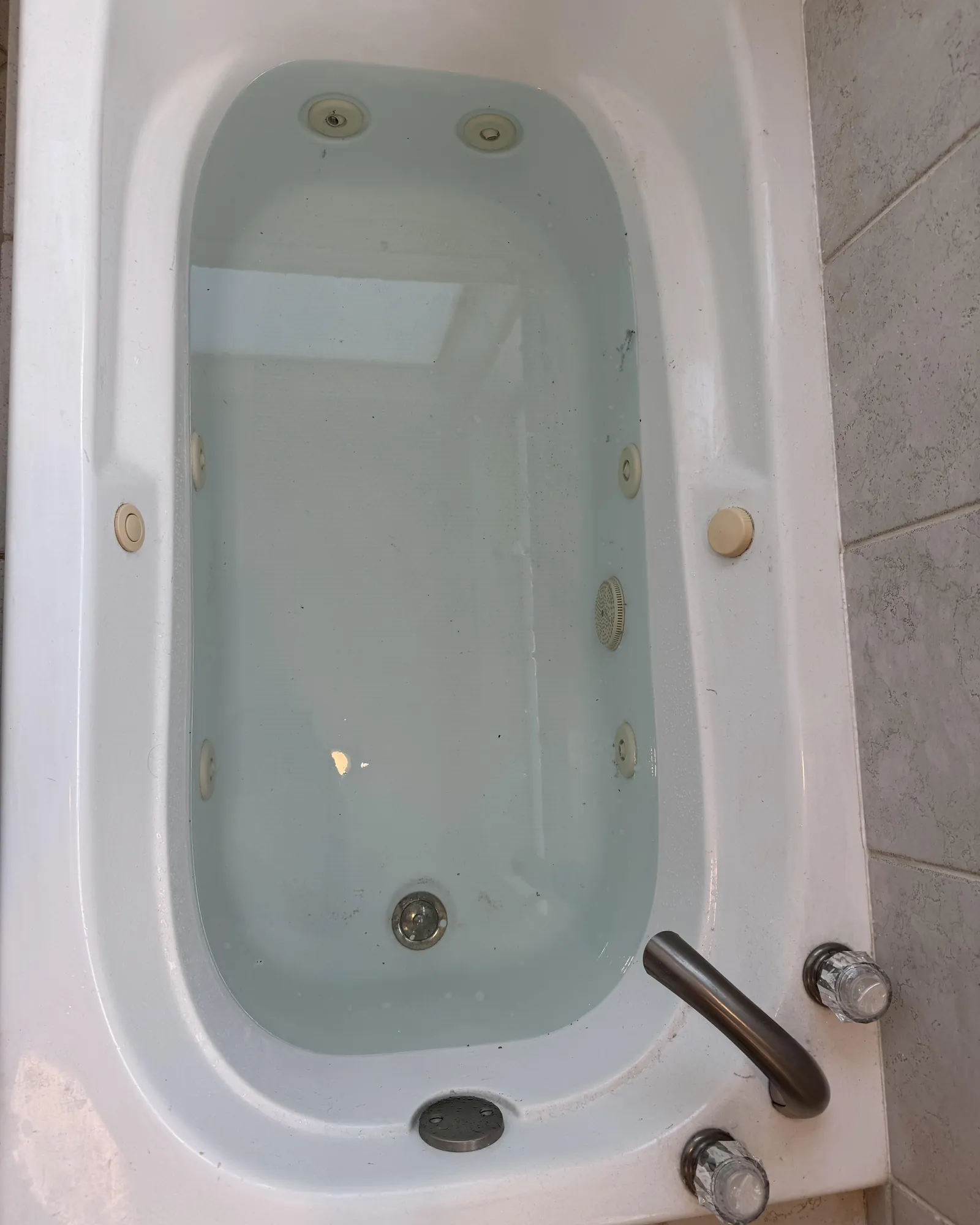 Person checking hot tub power switch near cabinet to stop unexpected jet activation.
