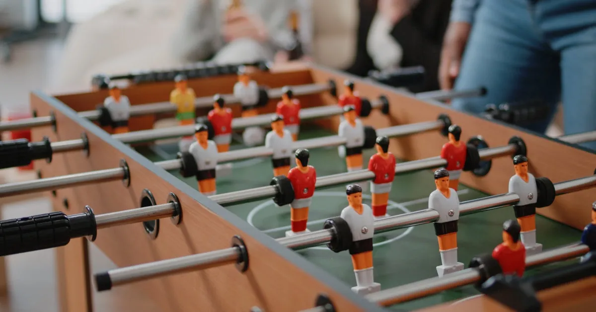 Person playing foosball seated showing light physical activity for health