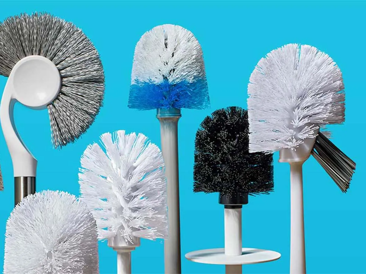 A person selecting a toilet brush from a wall-mounted holder in a bathroom.