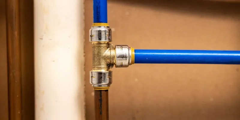 A professional crimping tool securing a copper ring onto a PEX pipe.