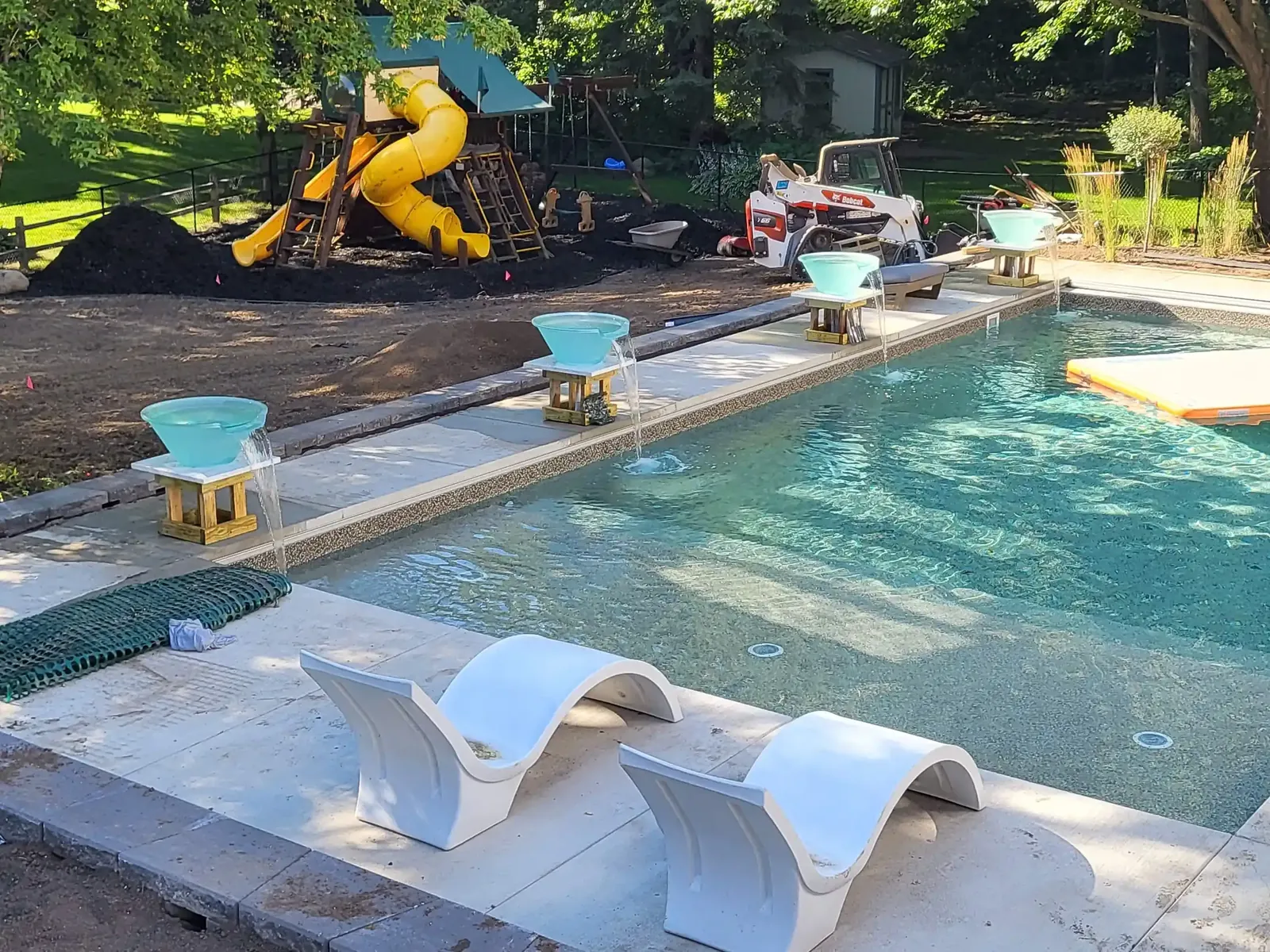 Professional pool maintenance tools rest on a concrete deck beside water.
