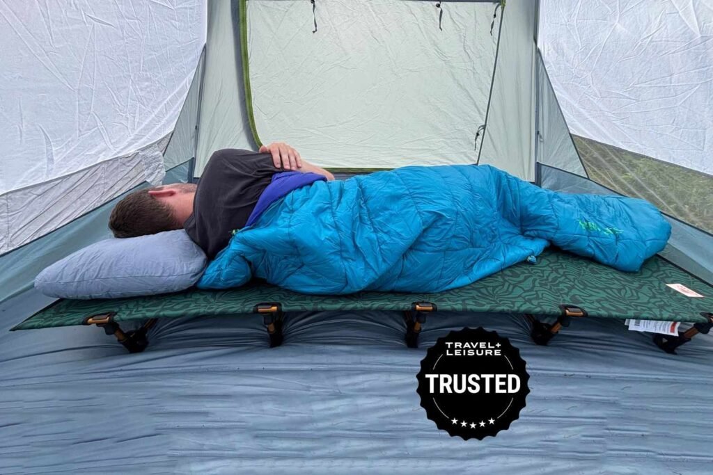 Queen size camping cot set up peacefully in a forest at twilight with natural soft lighting