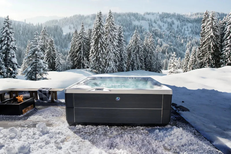 Residential hot tub on a snowy deck with a garden hose ready for filling.