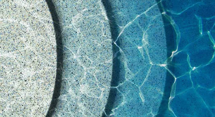 Resort pool with aqua blue mini pebble finish surrounded by tropical plants and rocks