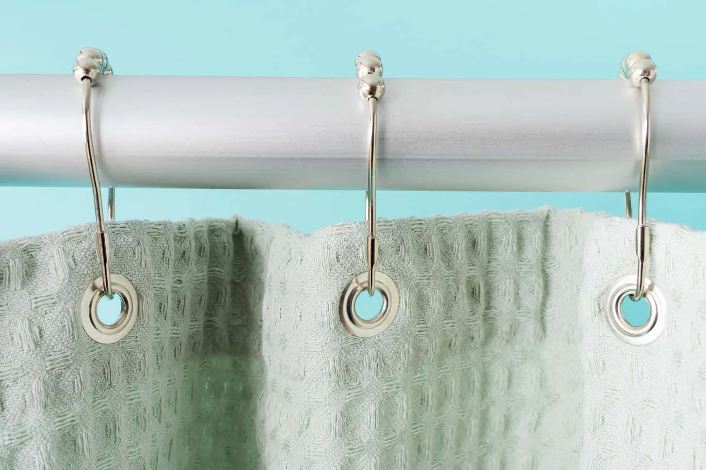 Samples of polyester, PEVA, and vinyl shower curtain liners laid on a countertop.