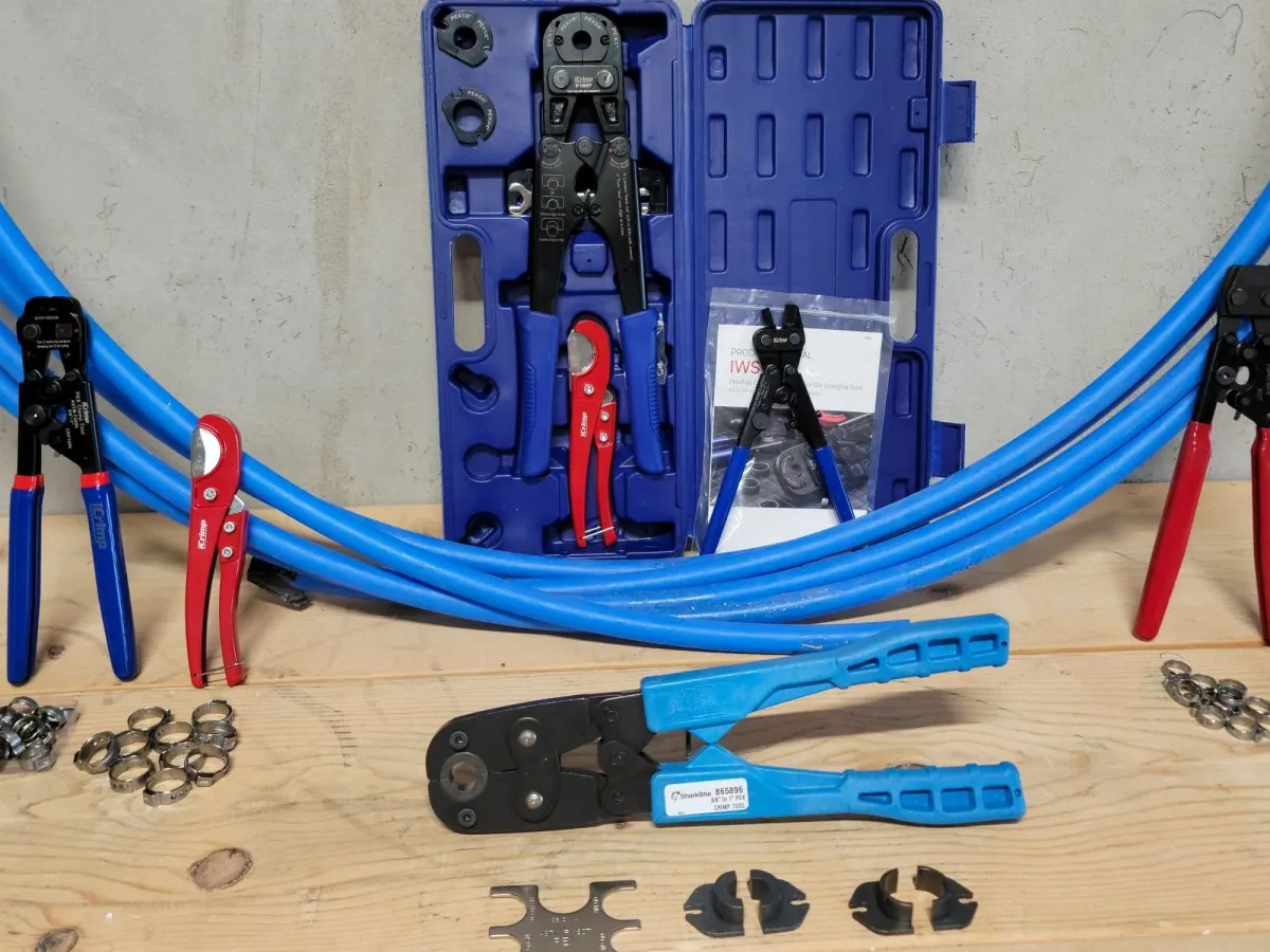A selection of various PEX crimp tools laid out for comparison before a plumbing project.