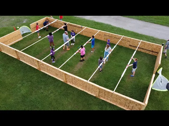 Setting up human foosball frame on a concrete driveway with assistants
