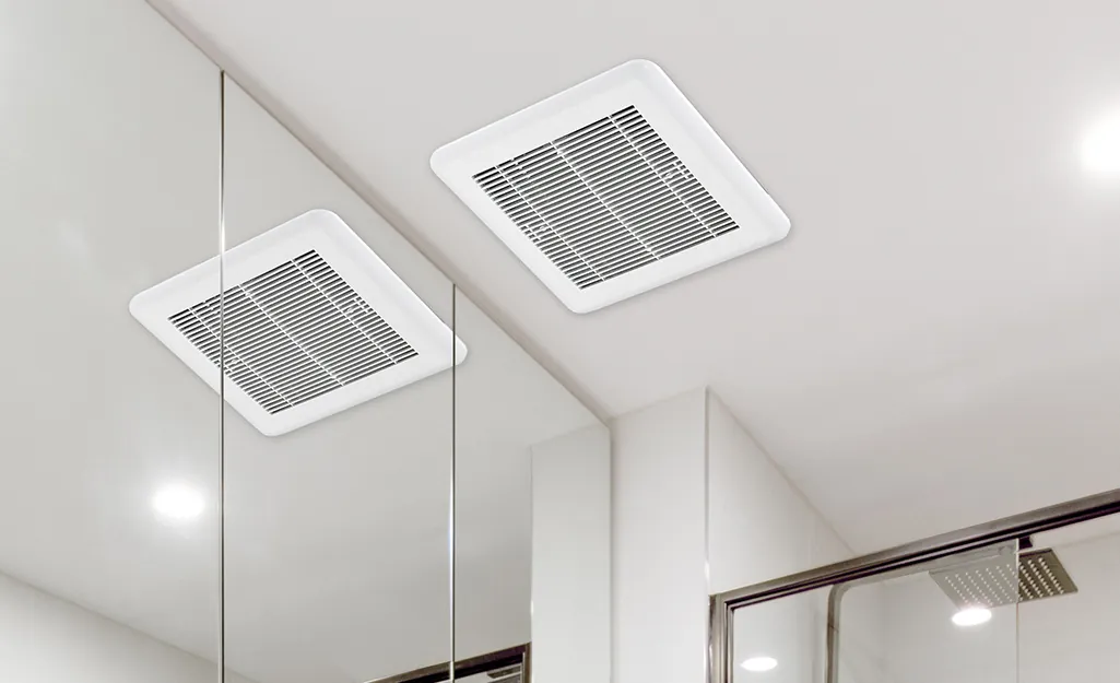 A smart bathroom exhaust fan with a glowing sensor mounted on tiled wall.