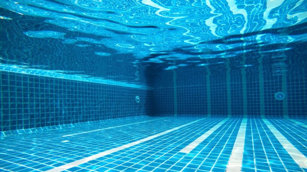 Sparkling blue salt water pool in a sunny backyard with warm lighting.