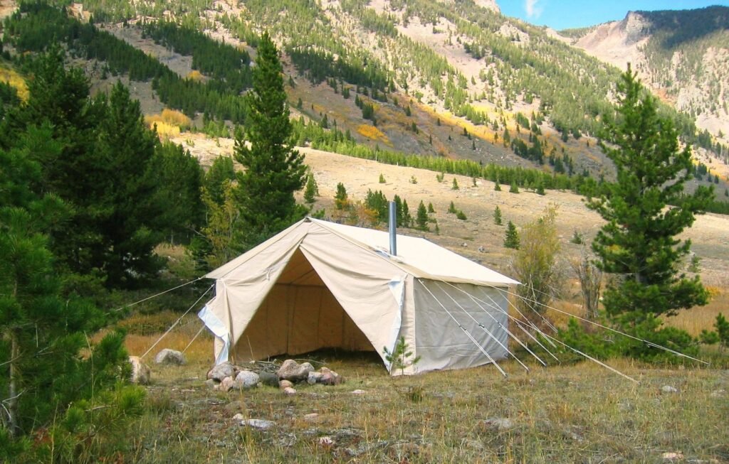Sturdy wall tent in a quiet forest clearing at dawn, perfect for hunting expeditions