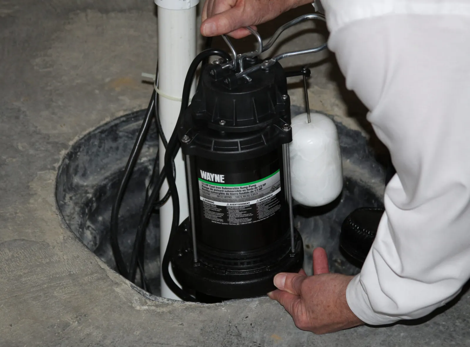 A submersible sump pump resting inside a clean basement drainage pit.