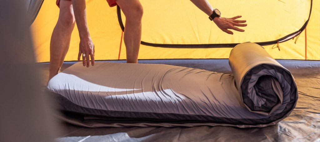 A supportive camping mattress on grass at dawn, ideal for bad back relief.