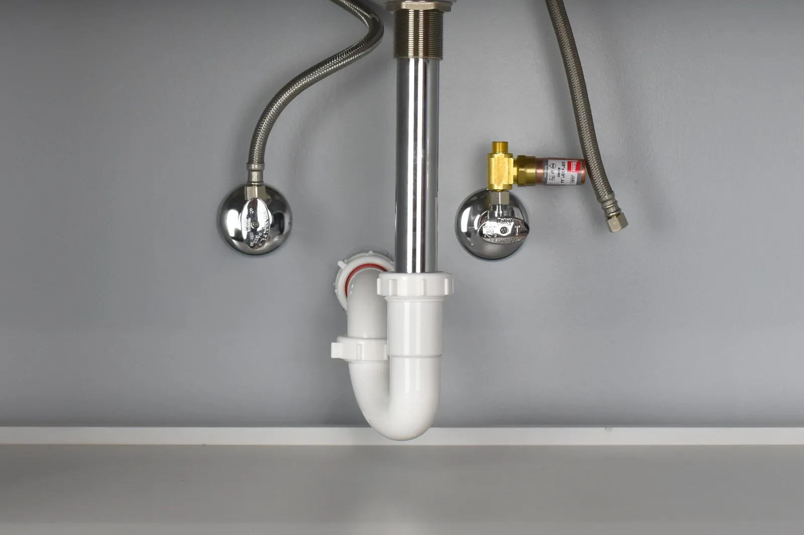 A tee-style water hammer arrestor installed on a washing machine hose connection.