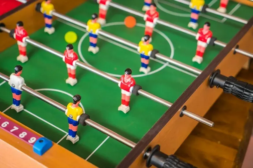Three connected foosball player figures on a metal rod with crisp detail