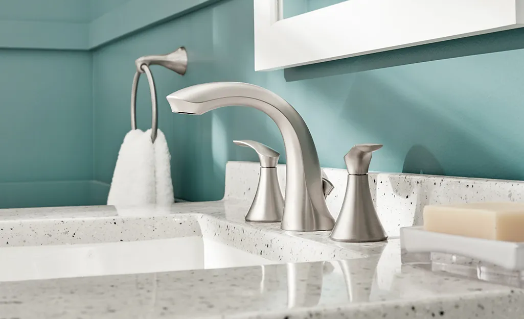 Three distinct types of bathroom faucets displayed neatly on a grey stone vanity.