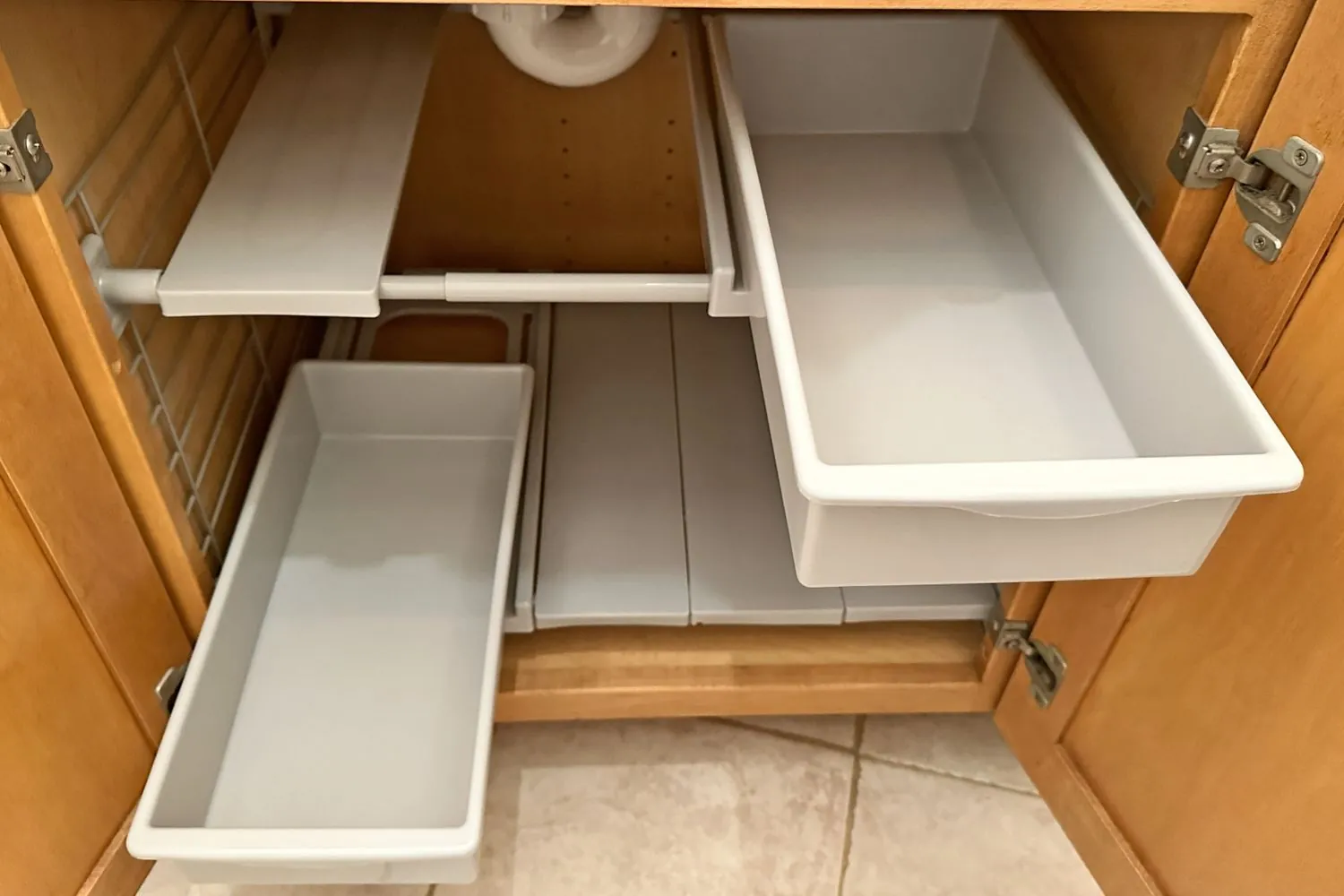 A U-shaped under-sink shelf maximizing storage space around bathroom plumbing pipes.