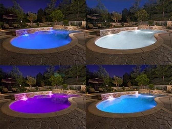 Underwater LED pool light glowing beneath clear water in a modern backyard setting.