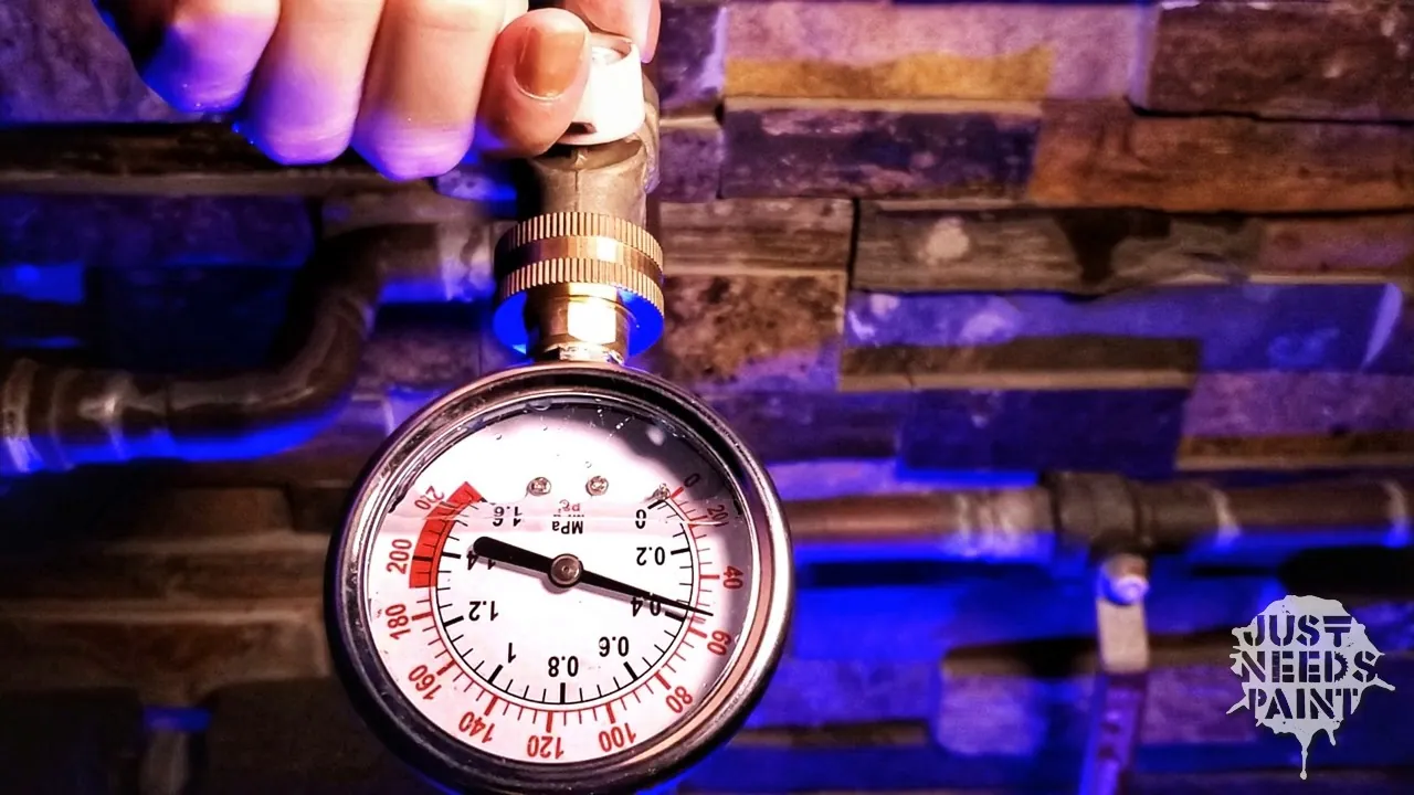 A water pressure gauge installed on a home main valve to monitor pressure.