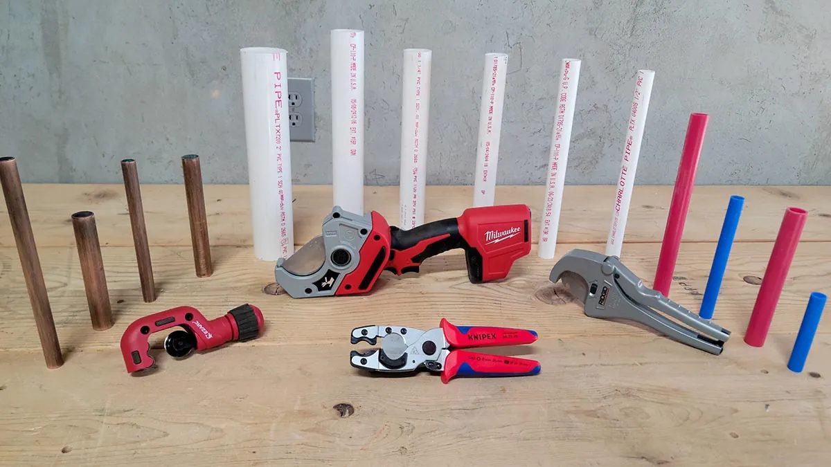 Wiping plastic debris from a PVC pipe cutter blade during routine maintenance.